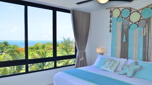 Un dormitorio con un ventanal grande, una cama con almohadones de estrella de mar y un tapiz con diseños circulares.