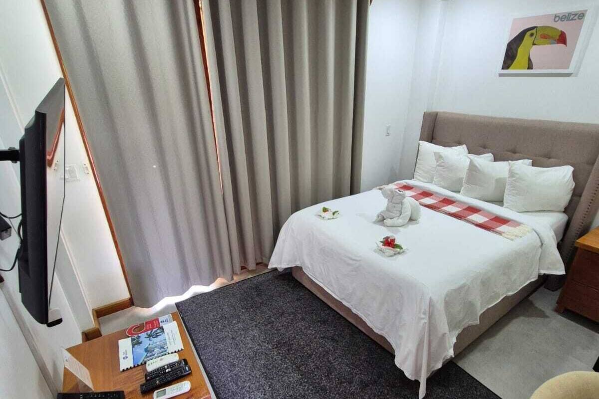 Ein Hotelzimmer mit Bett, Schreibtisch mit Computer, Stuhl, Fernseher und Deckenventilator.