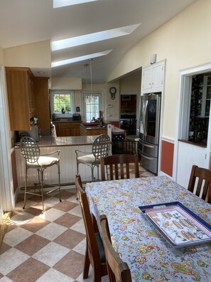 A spacious kitchen with a dining area, featuring a checkered floor, wooden chairs, and a table with a patterned tablecloth. - Historic intown waterfront w/PRIVATE dock & pool on 8.5 acres.  (Belfast)