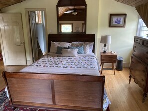 A bedroom with a wooden bed, a nightstand with a lamp, a dresser, and a mirror on the wall. - Historic intown waterfront w/PRIVATE dock & pool on 8.5 acres.  (Belfast)