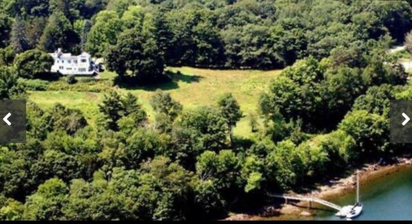 A large estate surrounded by dense forest, a body of water, and a sailboat. - Historic intown waterfront w/PRIVATE dock & pool on 8.5 acres.  (Belfast)