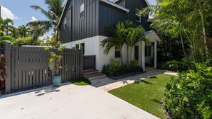 A modern two-story house with a dark exterior, white trim, and a well-maintained lawn. - OFF THE HOOK - 3 Bedroom / 3 Bathroom W/ Pool & Parking (Key West)