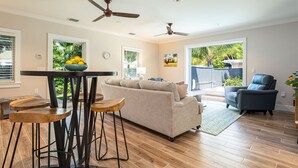 A spacious living room with a sofa, a dining table with stools, and a ceiling fan. - OFF THE HOOK - 3 Bedroom / 3 Bathroom W/ Pool & Parking (Key West)