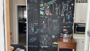 Una habitación con una pizarra llena de textos y dibujos, un armario de madera y un microondas sobre una encimera.