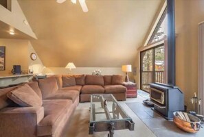 Cozy living area with a large sofa, fireplace, and high ceiling.