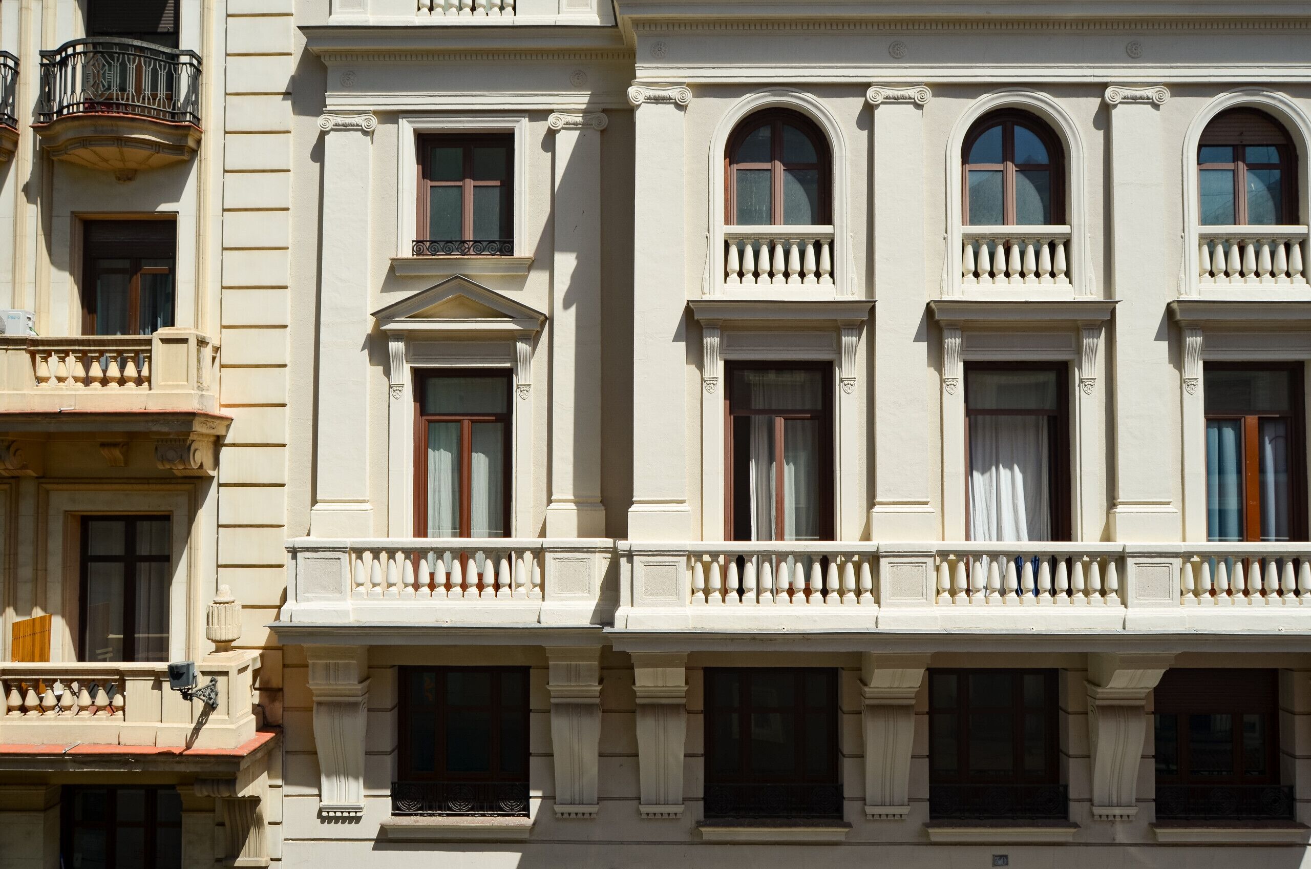 A multi-story building with classical architecture, featuring arched windows and decorative balustrades.