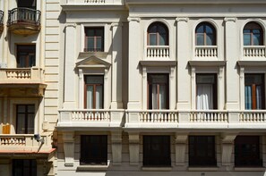 A multi-story building with classical architecture, featuring arched windows and decorative balustrades.
