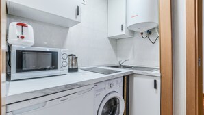 Eine kompakte Küche mit Mikrowelle, Toaster, Spüle und Waschmaschine.