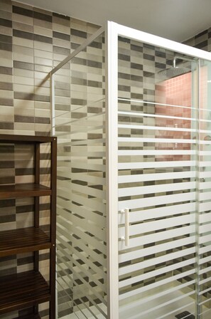 Une salle de bain avec un mur carrelé, un banc en bois et une cloison en verre.