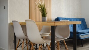 Ein moderner Essbereich mit Holztisch, weißen Stühlen und einer blauen Couch.