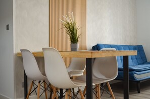 Un espace repas moderne avec une table en bois, des chaises blanches et un canapé bleu.