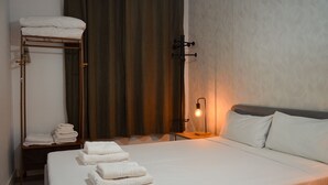Ein Hotelzimmer mit einem Bett, Handtüchern, einer Holzablage, einem Vorhang und einer Wandlampe.