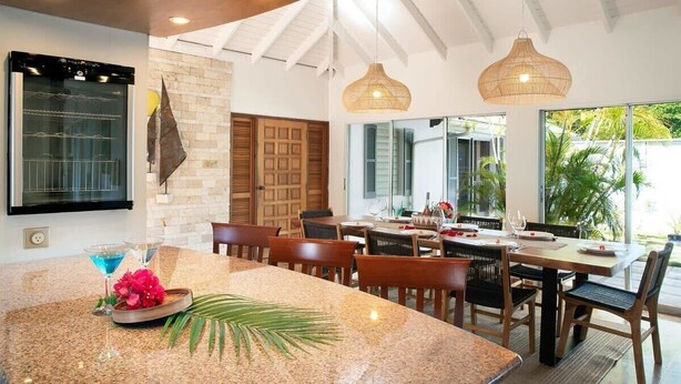Un comedor espacioso con una isla grande, sillas de madera y lámparas colgantes.