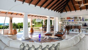 Un salón amplio con un sofá blanco, una estantería y vistas al exterior.