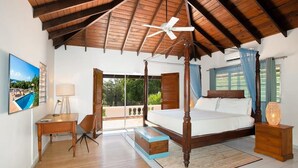 Un dormitorio con cama con dosel, ventilador de techo, escritorio, silla y vistas al exterior.