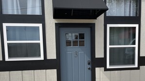 A building with a grey door, black trim, and two windows with white frames. - Former car wash bay apt. Unique!! (Mountain Home, Ar, 72653)