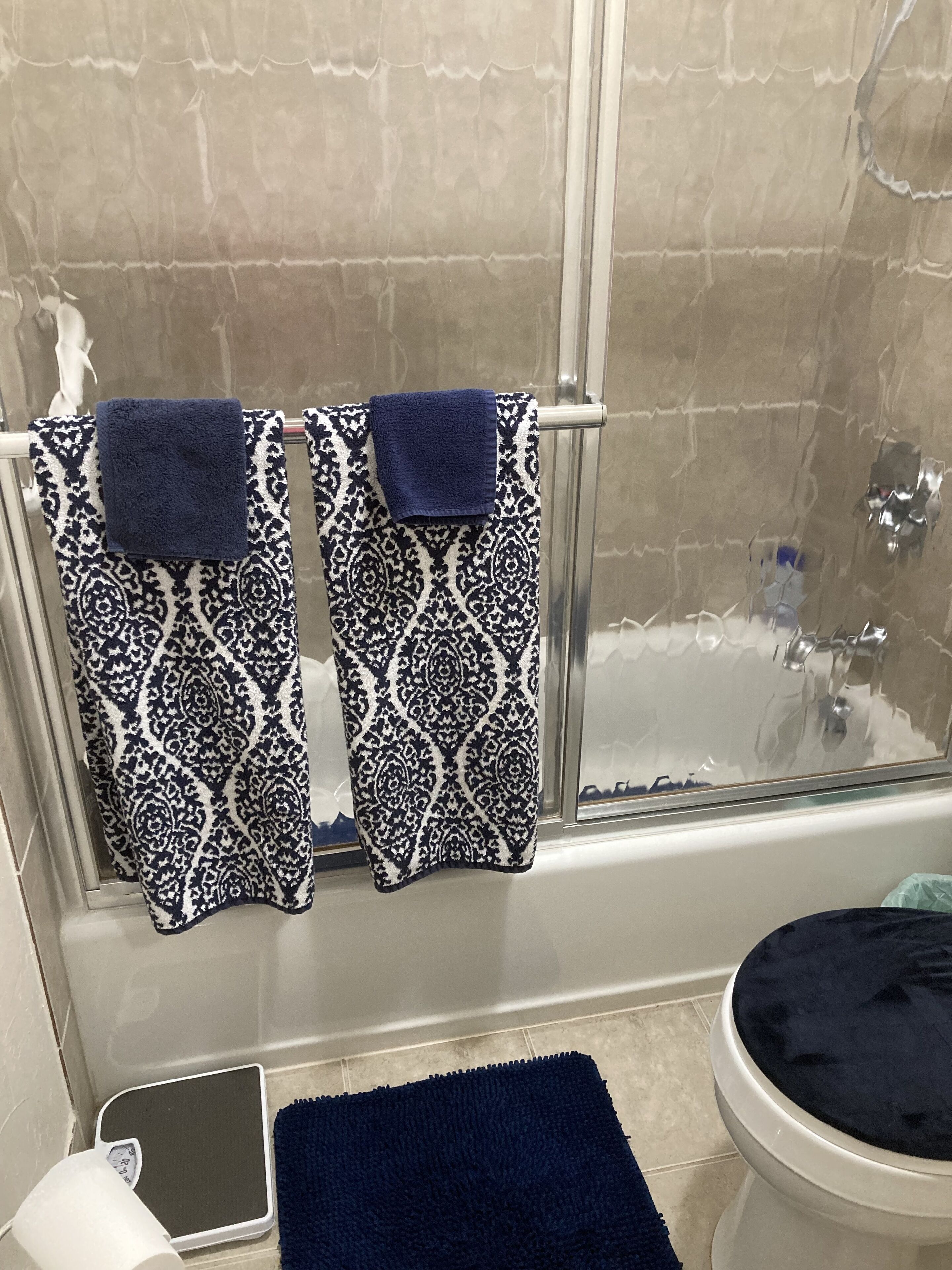 A bathroom with a bathtub, a toilet, and a shower. There are two patterned towels hanging on a towel rack.