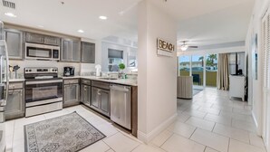 A modern kitchen with stainless steel appliances, a large island, and a view to the outside. - Aruba Collection (Daytona Beach Shores)