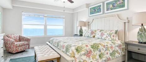 A bedroom with a bed, a bench, a chair, a nightstand, a lamp, and a ceiling fan.