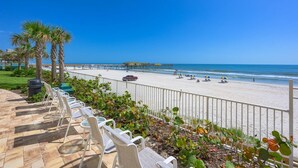 A beach with a wooden pier, white chairs, and a clear blue sky. - Aruba Collection (Daytona Beach Shores)