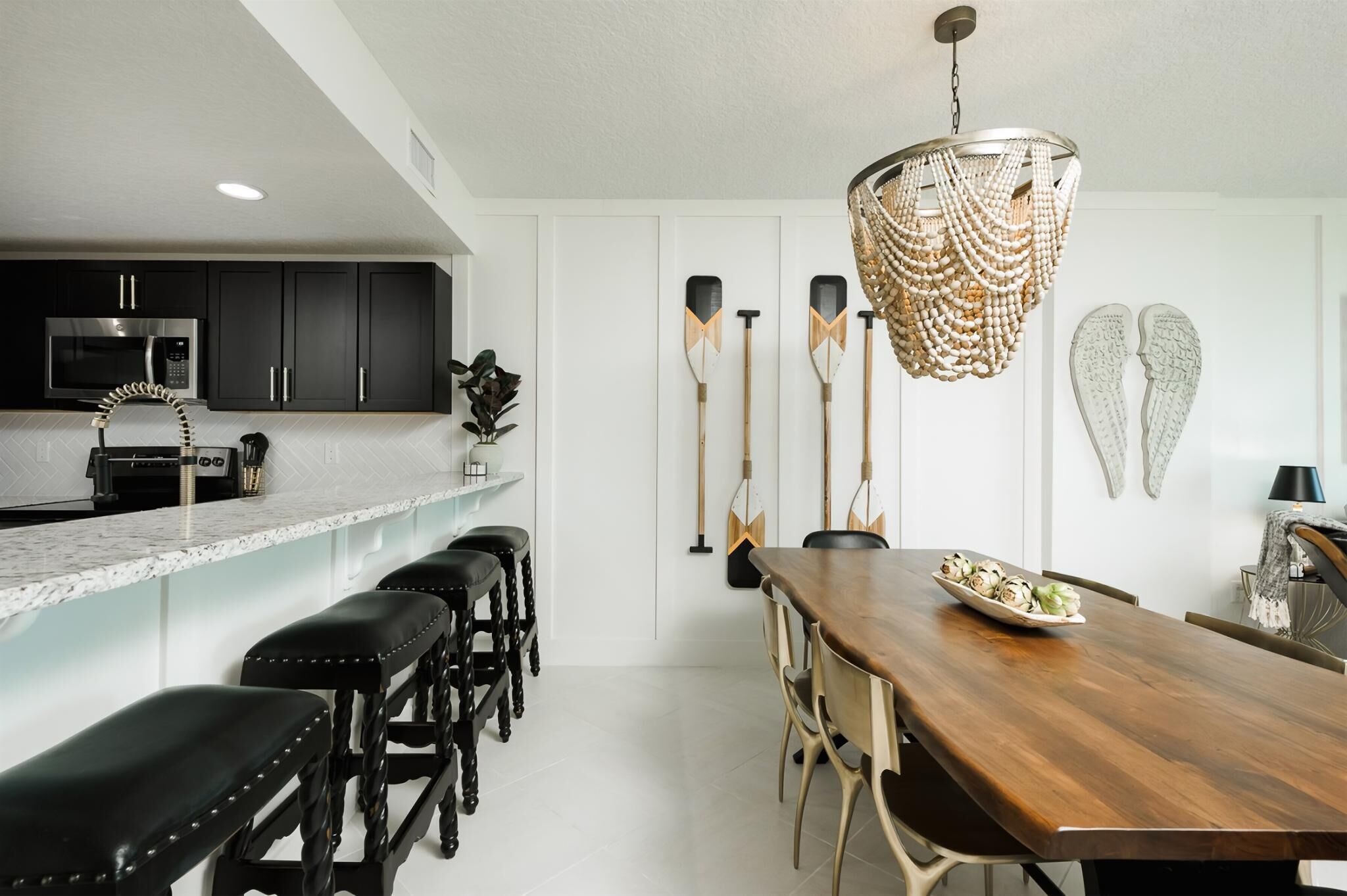 A modern kitchen with dark cabinets, a microwave, and a bar area with stools.