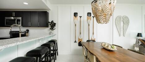 A modern kitchen with dark cabinets, a microwave, and a bar area with stools.