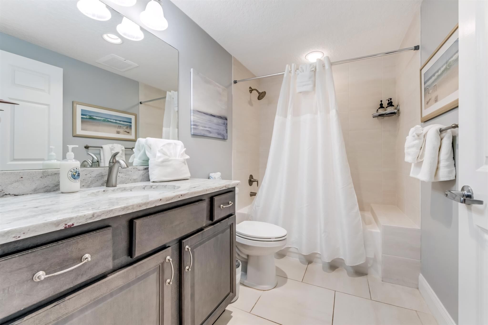 A bathroom with a marble vanity, a shower with a glass door, and a toilet.
