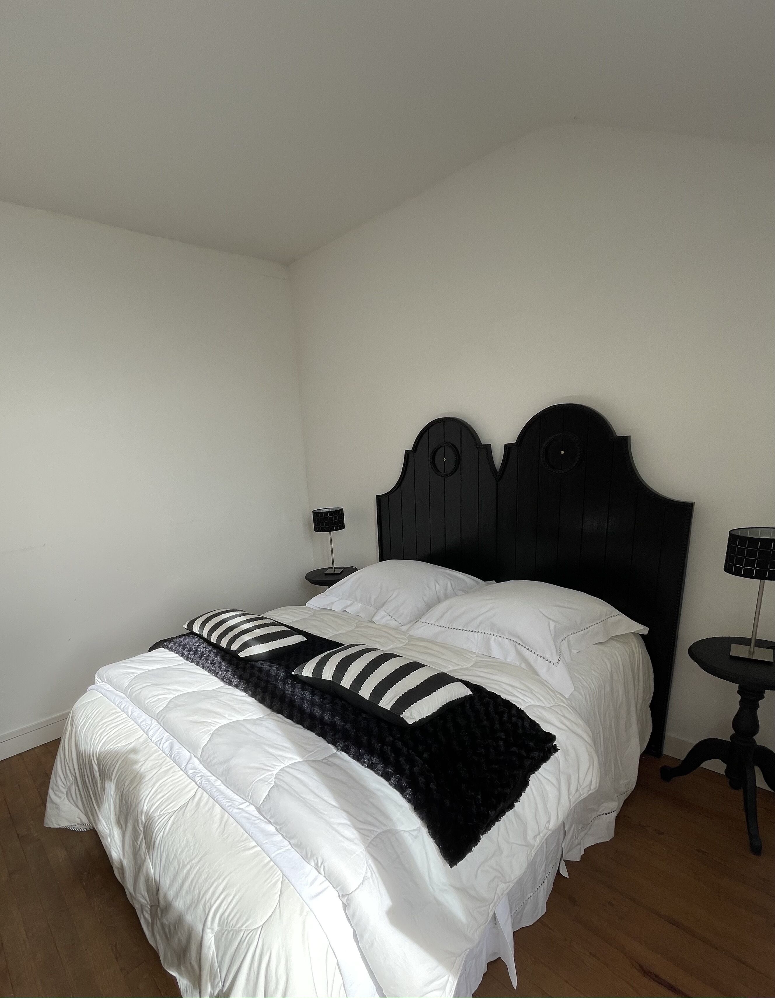 Une chambre à coucher avec un lit, deux tables de chevet et une petite table d’appoint.