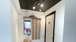 Un pasillo con un armario de madera, un espejo y una lámpara en el techo.