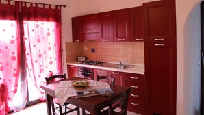 Une cuisine avec des meubles de rangement rouges, une cuisinière à gaz et un évier.