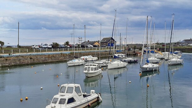 Un port de plaisance avec plusieurs bateaux amarrés, un petit bateau au premier plan et un bâtiment en arrière-plan.