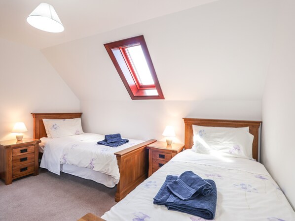 A bedroom with two beds, a skylight, and bedside lamps. - Woodburn Cottage (Waternish)