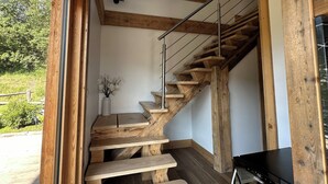 A wooden staircase with a glass ceiling, a dining table, and a black appliance. - Chalet Mont Blanc view with outdoor jacuzzi (Combloux)