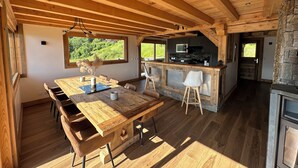 A wooden dining area with a large table, chairs, and a view of greenery outside. - Chalet Mont Blanc view with outdoor jacuzzi (Combloux)