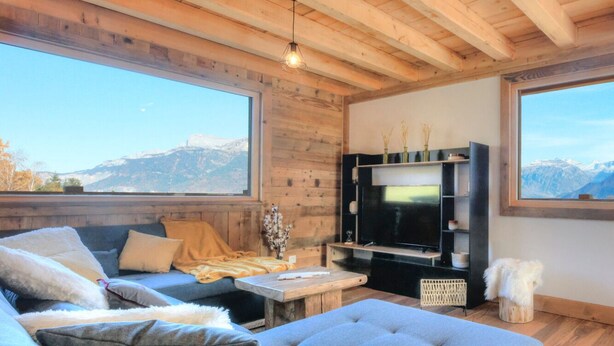 A cozy living room with a large TV, wooden furniture, and a mountain view. - Chalet Mont Blanc view with outdoor jacuzzi (Combloux)