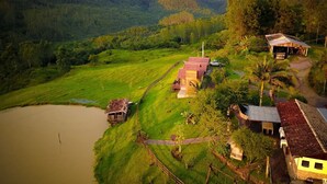 A rural property with a large open field, a small pond, and a few buildings with red roofs. - Pousada Rio Túnel (Grão Pará)
