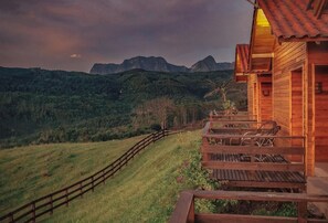 Una cabaña de madera con terraza de madera y vistas a montañas.