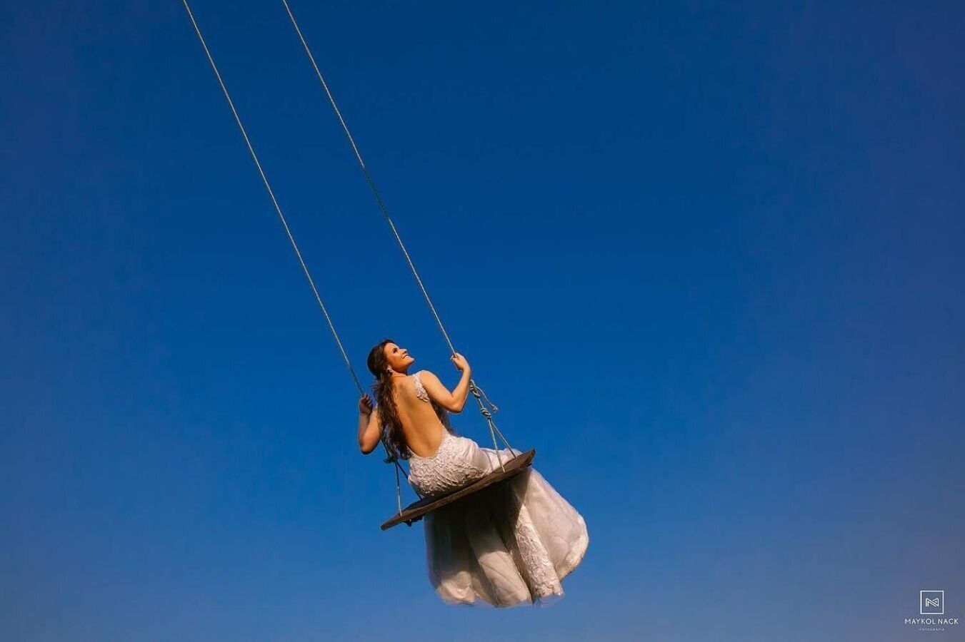 Una persona su un'altalena sospesa nell'aria sotto un cielo azzurro limpido.