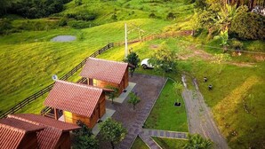 A rustic lodge with multiple wooden cabins, surrounded by lush greenery and a mountainous backdrop. - Pousada Rio Túnel (Grão Pará)