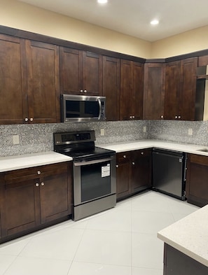 A kitchen with dark wooden cabinets, a stainless steel microwave, an LG stove, and a dishwasher.