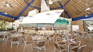 Ein Restaurant mit hoher Decke, einer großen Segelschiff-Dekoration und einem Koch hinter der Theke.