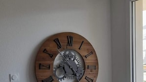 Una habitación con un reloj de pared grande, un equipo de aire acondicionado y un radiador.