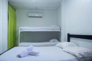 Camera con letto a castello, tenda verde, biancheria bianca e condizionatore d'aria.