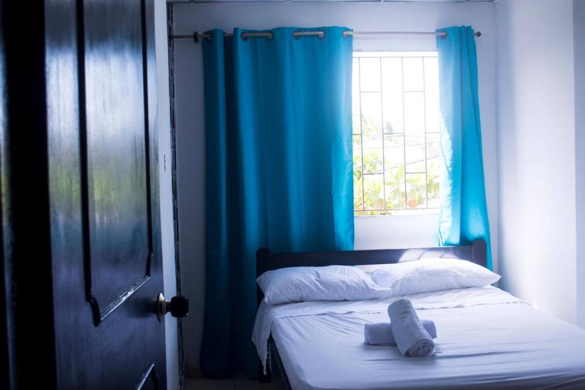 A room with a bed, a window with curtains, and a door.