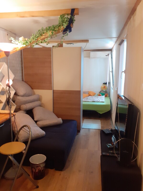 A compact room with a bed, a small table, a lamp, and a television.