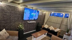 A modern living room with a flat-screen TV mounted on the wall, a sofa, a coffee table, and two armchairs.
