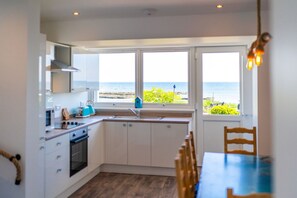 Een keuken met uitzicht op zee, een eettafel en een stoel.
