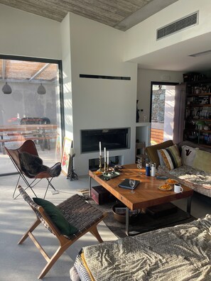 A modern living room with a wooden coffee table, leather armchair, and sofa with patterned cushions.