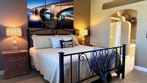 A bedroom with a bed, two bedside tables with lamps, a wall mural, and an arched doorway leading to another room. - Private Backyard w/Outdoor Kitchen & Boat Parking! (Lake Havasu City)
