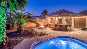 A backyard with a swimming pool, patio furniture, a fire pit, and a bar area with string lights. - Private Backyard w/Outdoor Kitchen & Boat Parking! (Lake Havasu City)